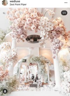 an image of flowers hanging from the ceiling in front of a wedding cake table with candles