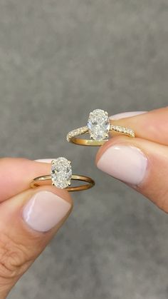 two women's hands holding gold and diamond engagement rings