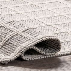 a white rug on top of a wooden floor next to a gray and white rug