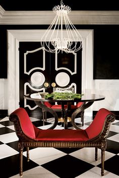 a dining room with black and white checkered flooring, chandelier and red chairs