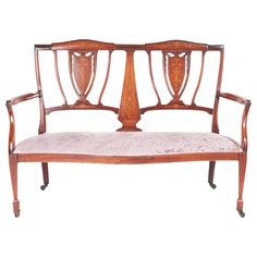 an antique wooden bench with upholstered back and arm rests against a white background