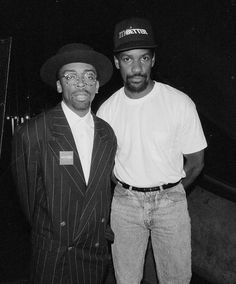 two men standing next to each other wearing hats