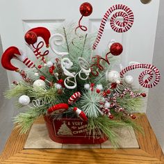 a christmas arrangement with candy canes and ornaments in a red bucket on a table