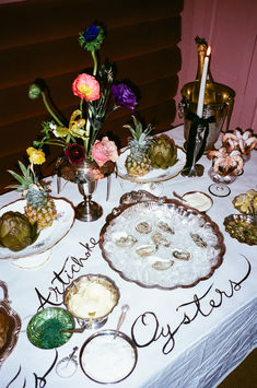 a table topped with plates and bowls filled with food next to a vase full of flowers