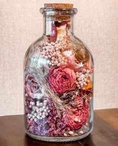 a bottle filled with lots of flowers on top of a wooden table