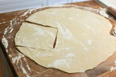 a wooden table topped with uncooked pizza dough