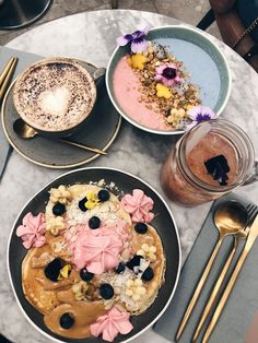 two plates of food on a table with utensils and spoons next to each other