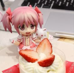 a doll sitting on top of a table next to a cupcake with strawberries