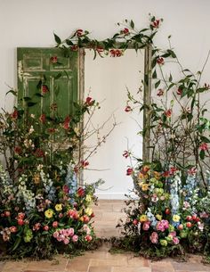 two mirrors with plants and flowers on them in front of a wall that has a green door