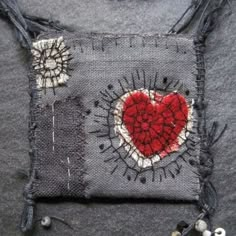 a piece of fabric with a red heart on it and some pins attached to it