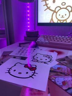 a desk with hello kitty pictures on it and a computer screen in the back ground