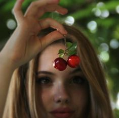 a woman with two cherries on her head and one cherry in the other's hand