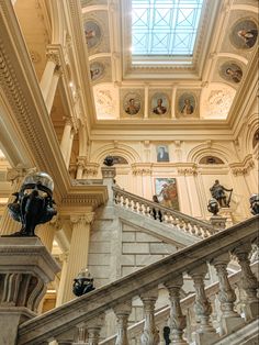 an ornate staircase in a building with paintings on the walls