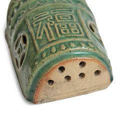 an old green ceramic object with holes in it