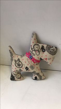 a small white dog figurine with black and pink designs on it's collar