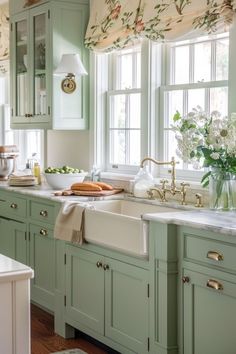 a kitchen filled with lots of green cupboards and white counter tops next to a window