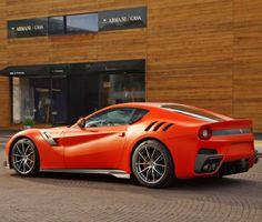 an orange sports car parked in front of a building