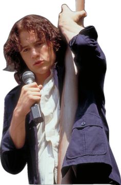 a young man holding a microphone up to his ear while standing next to a pole