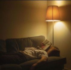 a man laying on a couch under a lamp