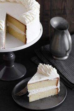 a white cake sitting on top of a plate next to a slice cut out of it