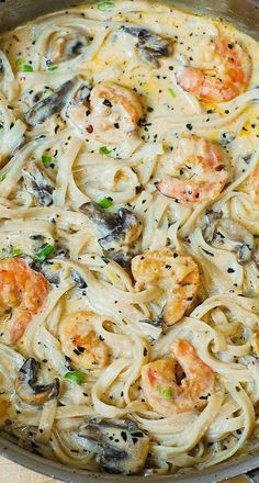 pasta with shrimp and mushrooms in a skillet on a wooden table, ready to be eaten