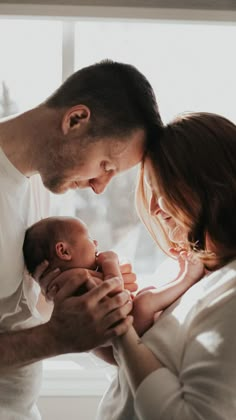 a man and woman holding a baby in their arms