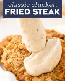 a fried steak is being drizzled with ranch dressing and served on a plate