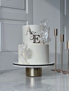 a three tiered wedding cake with white frosting and flowers on the top, sitting on a marble table