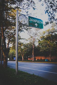 the street sign for janpath avenue is shown in front of some trees and bushes