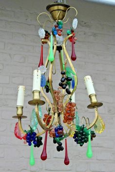 a chandelier hanging from the ceiling with colorful glass beads and candles on it