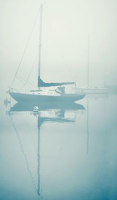 a sailboat floating in the water on a foggy day