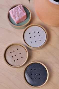 three ceramic bowls with holes in them sitting on a table next to a potted plant