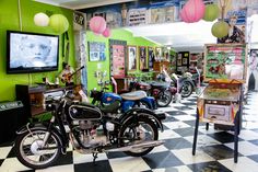 motorcycles are parked in a room with green walls and pictures on the wall behind them