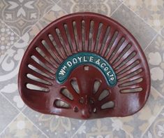 a close up of a red plastic object on a tile floor with the words wm doyle & cou written on it