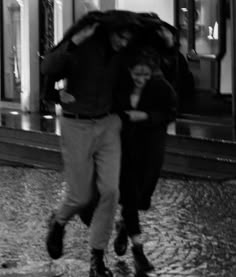 black and white photograph of two people walking in the rain