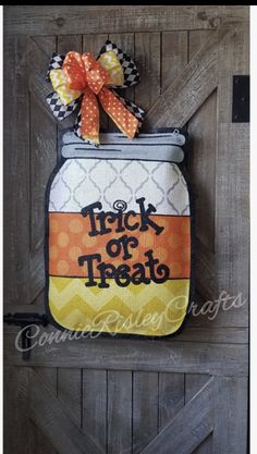 a trick or treat hanging on the side of a wooden door with an orange bow