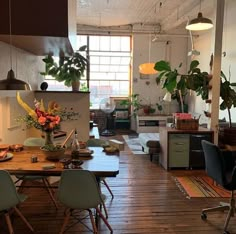 an open kitchen and dining area with wooden floors, potted plants on the wall