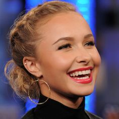 a close up of a person with a smile on her face and wearing large hoop earrings