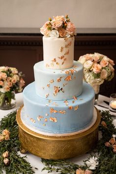 a three tiered cake sitting on top of a table next to flowers and candles