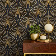 an art deco styled wallpaper with gold and black designs on the side table next to a plant