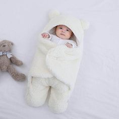 a baby wrapped in a bear blanket next to a teddy bear