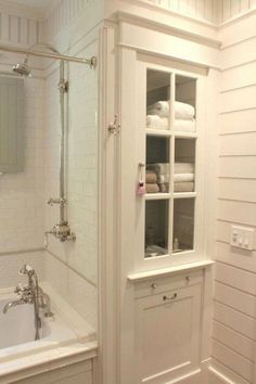 a bathroom with white walls and flooring next to a bathtub filled with towels