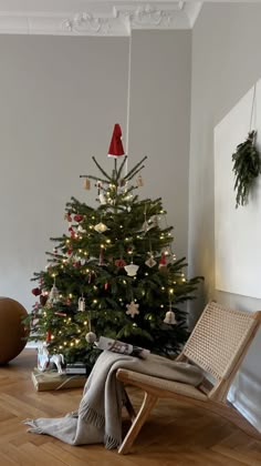 a small christmas tree in the corner of a room with a rocking chair next to it