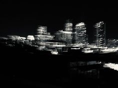 black and white photograph of city at night with light streaks on the building facades