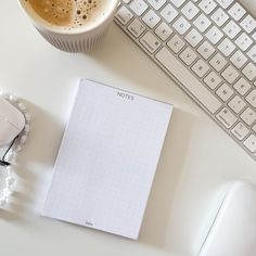 a cup of coffee sitting on top of a desk next to a keyboard and mouse