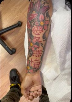 a person holding the hand of another person with flowers on their arm and writing in chinese