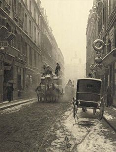 an old black and white photo of horses pulling carriages down a snowy street in the city