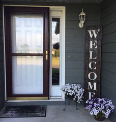 a welcome sign and flowers on the front porch