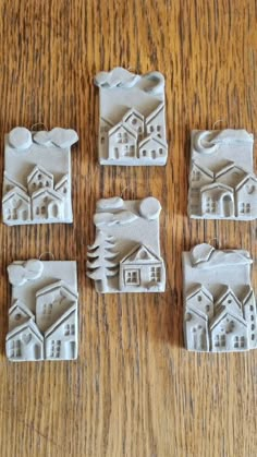 four white clay houses sitting on top of a wooden table