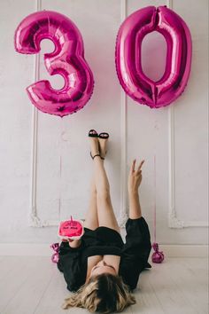 a woman laying on the floor with her legs up in front of balloons and numbers